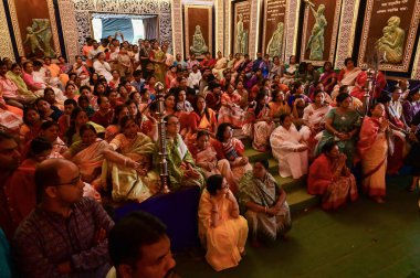 Howrah, Batı Bengal, Hindistan -11.10.2024: Hintli kadınlar Tanrıça Durga 'ya tapınıyor ve oturuyorlar, sondhipujo sırasında, puja Ashtami ve nabami arasında. Geleneksel Bengali puja ritüeli.