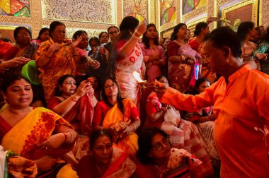 Howrah, Batı Bengal, Hindistan -11.10.2024: Hintli kadınlar kutsal pradip, lamba, sondhipujo, puja, ashtami ve nabami arasında ısınmak için uzanıyorlar. Geleneksel Bengali puja ritüeli.