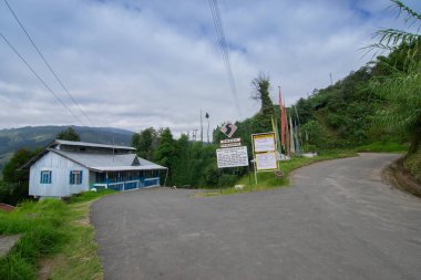Okhrey köyüne giden güzel bir yol, renkli Buddist dua bayrağı yolun diğer tarafında dalgalanıyor. Okhrey arka planda doğal manzarası olan uzak bir köydür, Sikkim, Hindistan 'da..