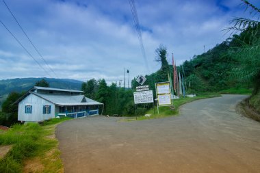 Okhrey köyüne giden güzel bir yol, renkli Buddist dua bayrağı yolun diğer tarafında dalgalanıyor. Okhrey arka planda doğal manzarası olan uzak bir köydür, Sikkim, Hindistan 'da..