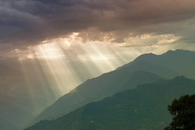 Rabangla, Sikkim, Hindistan 'dan gelen güneş ışınları. Ön planda Slihoutte ağaçları ve arka planda Himalaya dağları. Sikkim 'li Büyük Himalayalar' ın muhteşem manzarası..