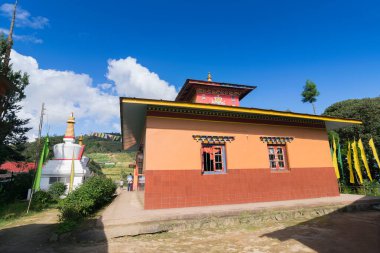Sikkim, Hindistan 'daki Okhrey Köyü' nde güneşli bir Budist Manastırı. Yukarıda mavi bulutlu gökyüzü ve arkada Himalaya Dağları.