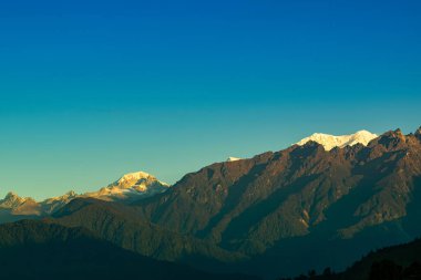 Kanchenjugha Dağı, Himalaya sıradağları, Sikkim, Hindistan 'da güneşin doğuşundan güzel bir gün ışığı. Şafak vakti dağlarda turuncu renkler