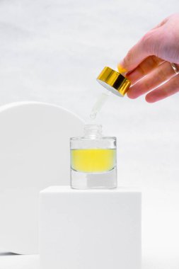 Woman holds pipette and transparent glass bottle with natural essential oil or organic serum. She ready to start skin care procedures. Concept of home body care and healthy lifestyle. Close-up front view