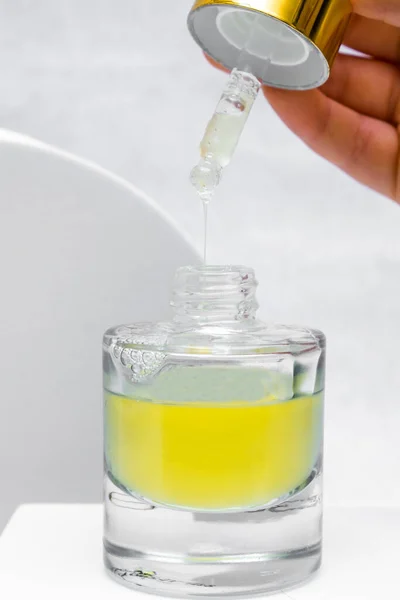 Bottle pipette dropper and Liquid yellow-orange retinol or vitamin c gel or serum on a white background