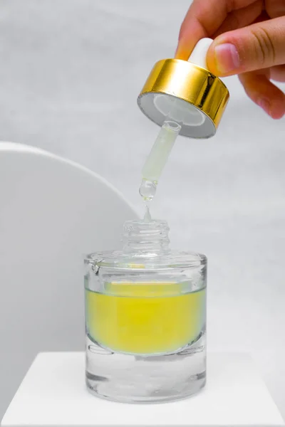 Bottle pipette dropper and Liquid yellow-orange retinol or vitamin c gel or serum on a white background