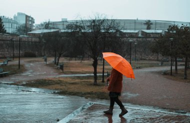 Yağmurlu bir günde parkta yürüyen küçük kız.