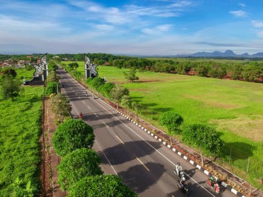 Purwakarta 'daki sınır kapısının hava görüntüsü. Geleneksel kapı ve yeşil tarlaları olan asfalt yolların insansız hava aracı görüntüsü. 