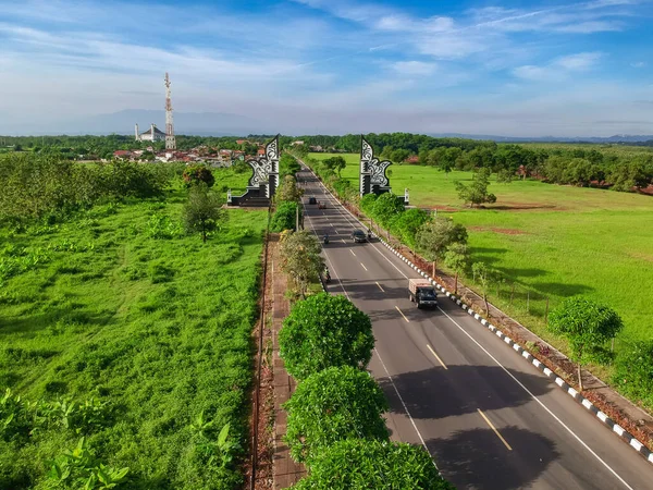 Purwakarta 'daki sınır kapısının hava görüntüsü. Geleneksel kapı ve yeşil tarlaları olan asfalt yolların insansız hava aracı görüntüsü. 