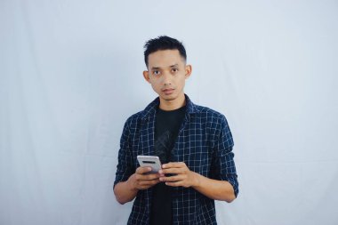 Yakışıklı Asyalı adam, beyaz arka planda okunmuş ticaret ve sohbet sonrasında cep telefonu ekranına şaşırmış görünüyor.