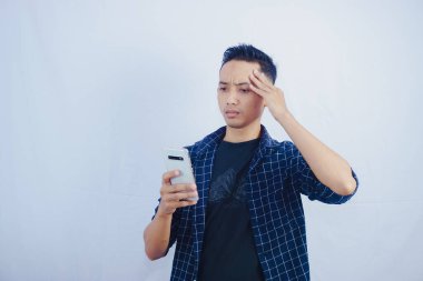 Yakışıklı Asyalı adam, beyaz arka planda okunmuş ticaret ve sohbet sonrasında cep telefonu ekranına şaşırmış görünüyor.