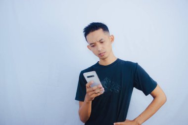 Kafasında akıllı telefon olan siyah tişörtlü bir adam kameraya bakıyor. 