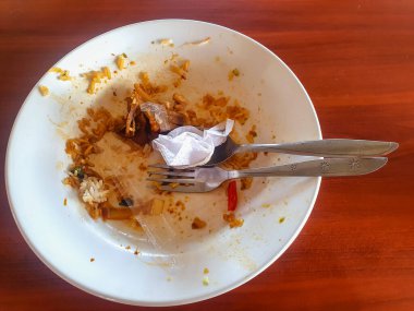 Kirli tabaklar ve yemek artıklarıyla dolu kirli kaşıklar ve restoran masasında kullanılmış mendiller..