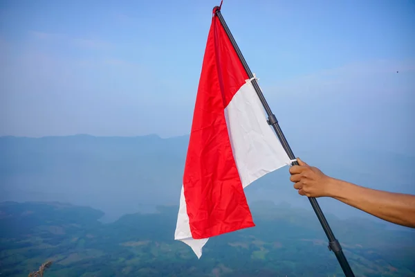 青い空を背景にインドネシア国旗を手に持っている インドネシア独立記念日 国民の休日と幸せなお祝いの概念 — ストック写真