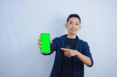 Akıllı telefon tutan Asyalı genç bir adam. Reklam için en iyi yeşil ekran şablonunu gösteren ekran telefonu.