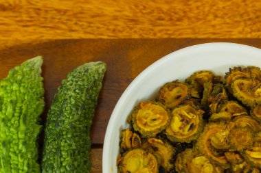 Fresh green organic Bitter gaud vegetable kept along with cooked bitter gaud on a wooden table with copy space