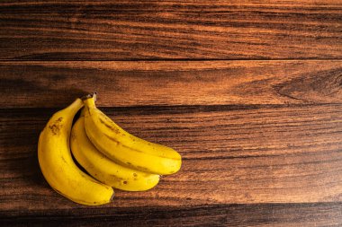 A bunch of ripe bananas kept on a wooden table with copy space 