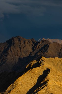 Dağların siluetinin dramatik bir görüntüsü. Güneş ışınları bulutlarla birlikte düşüyor.