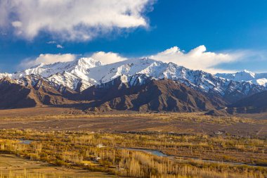 Karla kaplı dağların panoramik manzarası Ladakh 'ta gökyüzünde bulutlarla kaplı.