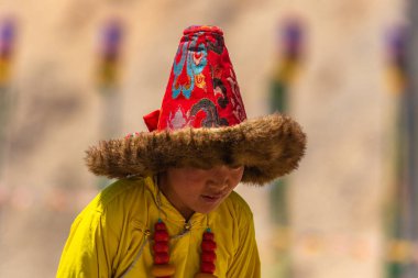 23 Mayıs 2024 'te Leh, Ladakh Hindistan' da sarı bir kostüm ve kürk şapka giyen Tibetli bir çocuğun portresi.. 