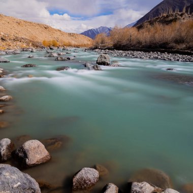 Yüksek irtifa dağları arasında akan İndus Nehri manzaralı bir manzara..