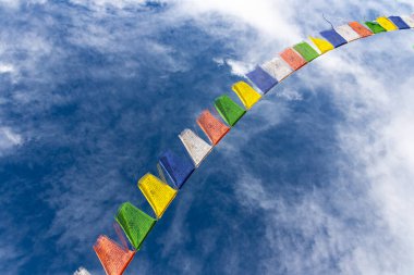 Bulutlu mavi gökyüzü karşısında renkli Tibet dua bayrakları   