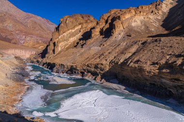 Donmuş Zanskar nehri Ladakh 'ın engebeli dağ sıralarından akıyor..
