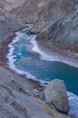 Zanskar Nehri 'nin mavi suları, kışın kenarlarında donarak dağların arasından akar..