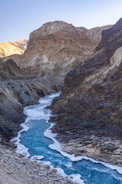 Zanskar Nehri 'nin mavi suları, kışın kenarlarında donarak dağların arasından akar..