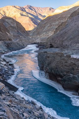 Zanskar Nehri 'nin mavi suları, kışın kenarlarında donarak dağların arasından akar..