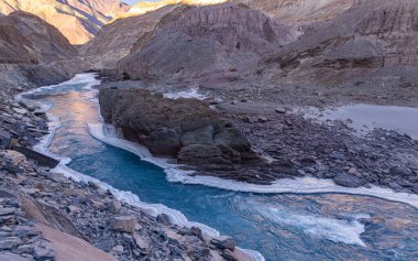 Zanskar Nehri 'nin mavi suları, kışın kenarlarında donarak dağların arasından akar..