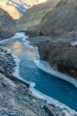 Zanskar Nehri 'nin mavi suları, kışın kenarlarında donarak dağların arasından akar..