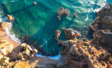 Portekiz, Algarve 'deki Camilo plajında güneş doğarken yüksek açılı kaya oluşumu manzarası