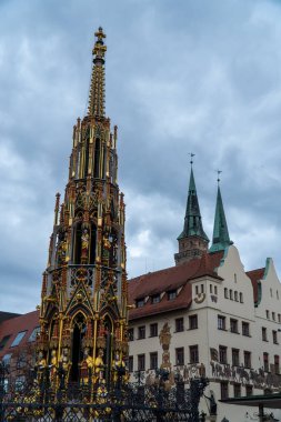 NUREMBERG, ALMANY - 22 Kasım 2022: güzel Schoner Brunnen çeşmesi bulutlu bir günde. Almanya 'nın Nuremberg kentindeki Hauptmarkt meydanında yer almaktadır.