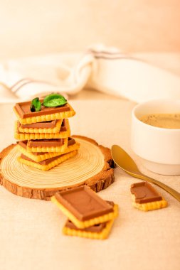 Yuvarlak ahşap tepside yığılmış zengin çikolatalı kurabiyeler. Bir tanesi ısırılmış. Hafif arkaplan.