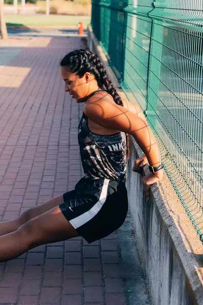 Spor giyimli bir kız, sokakta güç egzersizi yapıyor. odak arkaplanı dışında.