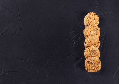 Koyu beton arka planda tahıl ve tahıllardan yapılmış birkaç tahıllı kurabiye. Boşluğu kopyala, üst görünüm