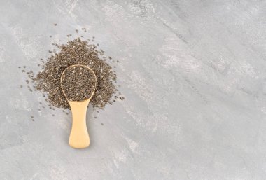 Boş bir beton arka planda tahta kaşıkta Chia tohumları, üst manzara. Boşluğu kopyala