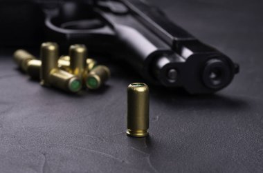 9mm 'lik tabanca. Koyu beton arka planda boş kartuş var.