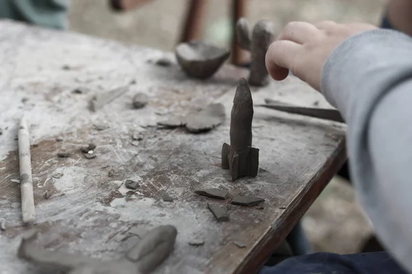 Bir çocuğun eli çekiç ve keskiyle atölyede.