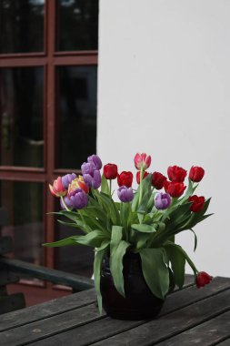 Ahşap bir masadaki vazoda kırmızı güllerin yakın çekimi.