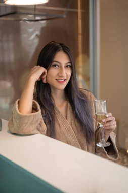 taking a break in a spa young woman with long black hair, holds a glass of champagne while sitting resting, lifestyle and beauty