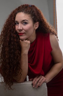 beautiful face female model wears makeup with red lips and has long curly hair, young latin woman portrait in studio