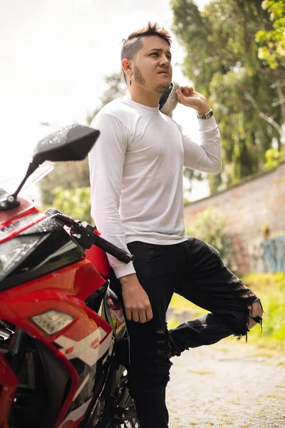 adventurer young latin man smiling, casual fashion near modern motorcycle, transportation and freedom, male model