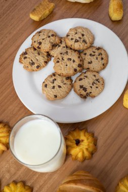 Lokanta masasının duvar kağıdı, yanında bir bardak süt, yanında çikolata parçacıklı kurabiyeler, lezzetli içecekler ve ev yapımı yemekler, iştah açıcı atıştırmalıklar.