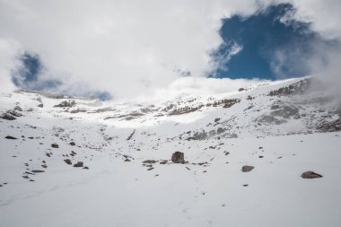 Karlı, kayalı ve bulutlu bir dağın doğal manzarasının ayrıntıları, soğuk havalı duvar kağıdı, güneşli bir dış, turistik bir yer.