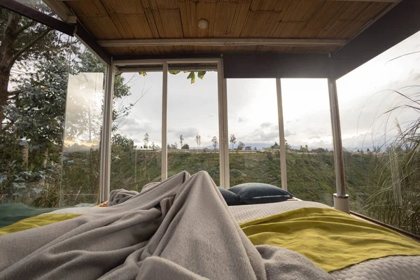 Rahat ve rahat bir yaşam tarzı, battaniyeli bir yatak odası arka planda bitkiler olan büyük pencereli bir yatak odası, tatil için turistik bir yer.