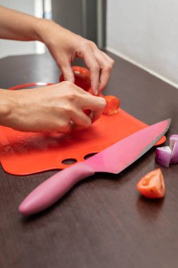 Masa ayrıntıları, doğrama tahtası, taze bir domatesi bıçakla dilimleme, sağlıklı yemek hazırlama, salata ve çatal bıçak.