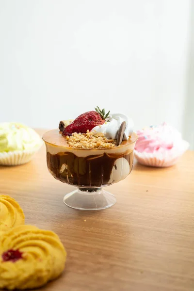 appetizing cup with ice cream, cream, strawberries in the background cookies, sweet desserts on studio table as wallpaper, pastry and confectionery