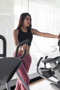 Spor giyim, beden eğitimi, sağlıklı yaşam tarzı ve hobileri olan çekici Latin kadın eğitim için makineler, detaylar.